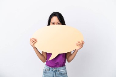 Beyaz arka planda izole edilmiş genç Vietnamlı kadın arkasında saklanan boş bir konuşma baloncuğu tutuyor.