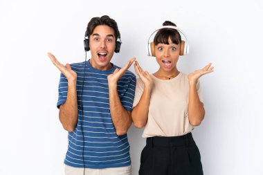 Beyaz arka planda izole edilmiş genç melez arkadaşlar şaşırdılar ve müzik dinlediler.