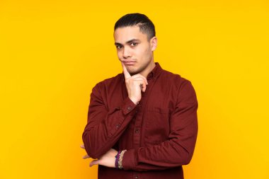 Asyalı yakışıklı adam sarı arka planda izole edilmiş şüpheli hareketler yapıyor.