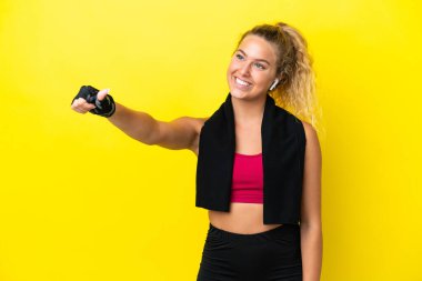 Sarı arka planda izole edilmiş havlusu olan sporcu kadın baş parmak hareketi yapıyor.