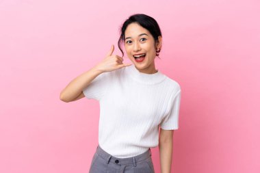 Pembe arka planda izole edilmiş genç Vietnamlı kadın telefon jesti yapıyor. Bana geri dönüş işareti ver.