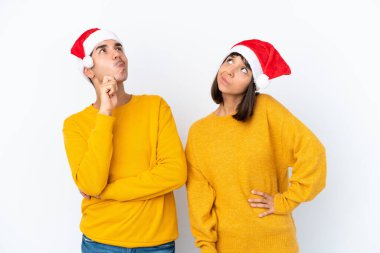 Genç melez çift, Noel 'i beyaz arka planda izole bir şekilde kutlarken kafalarını kaşıyarak bir fikir üretiyor.