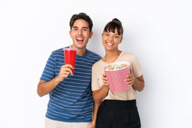 Beyaz arka planda izole edilmiş genç melez arkadaşlar ellerinde koca bir kova patlamış mısır tutuyorlar.