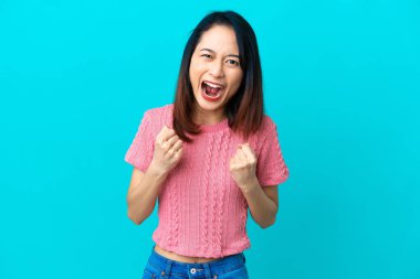 Genç Vietnamlı kadın mavi arka planda izole edilmiş. Kötü bir durum yüzünden hayal kırıklığına uğramış.