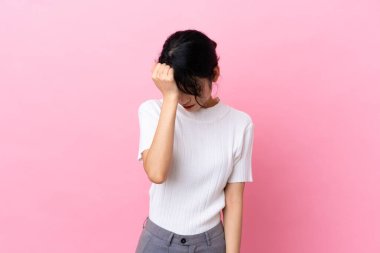 Genç Vietnamlı kadın pembe arka planda izole edilmiş, baş ağrısı var.
