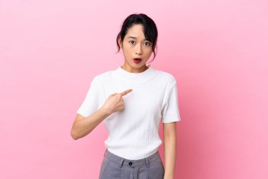 Pembe arka planda izole edilmiş genç Vietnamlı kadın kendini işaret ediyor.