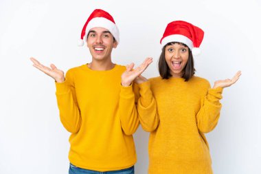 Genç melez çift Noel 'i beyaz arka planda yalnız kutluyor. Şaşırmış ve şok olmuş bir yüz ifadesi var.