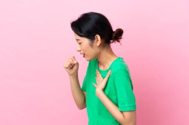 Pembe arka planda izole edilmiş genç Vietnamlı kadın çok öksürüyor.