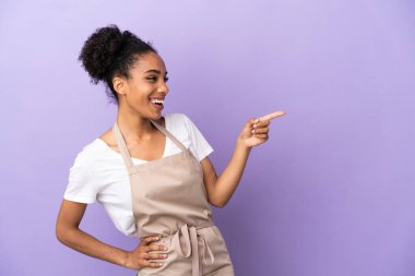 Restoran garsonu, latin kadın, mor arka planda izole edilmiş, parmağını yana doğru uzattı ve bir ürün sundu.