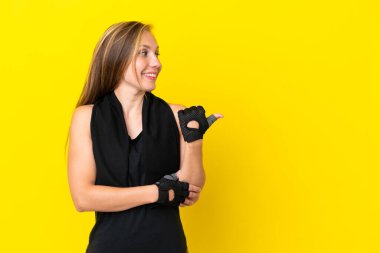 Beyaz arka planda izole edilmiş genç İngiliz kadın bir ürün sunmak için kenarı işaret ediyor