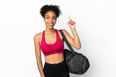 Spor çantalı genç Afro-Amerikan kadın mavi arka planda izole edilmiş ve en iyinin işareti olarak parmağını kaldırıyor.