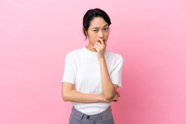 Pembe arka planda izole edilmiş genç Vietnamlı kadın sağa bakarken şaşırmış ve şok olmuştu.