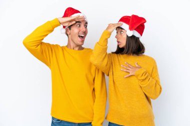 Genç melez çift Noel 'i beyaz arka planda yalnız kutluyor. Şaşırmış ve şok olmuş bir yüz ifadesi var.
