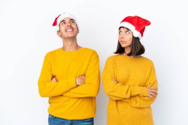 Genç melez çift Noel 'i beyaz arka planda izole bir şekilde kutluyor gülümserken yukarı bakıyor