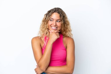 Beyaz arka planda izole edilmiş kıvırcık saçlı kız yana bakıyor ve gülümsüyor.