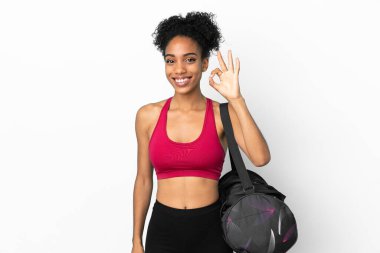 Spor çantalı genç Afro-Amerikalı kadın mavi arka planda izole edilmiş. Parmaklarıyla işaret veriyor.