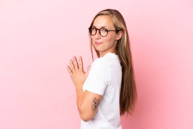 Pembe arka planda izole edilmiş genç İngiliz kadın bir şeyler planlıyor.