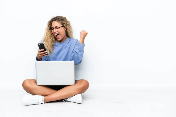 Kıvırcık Saçlı Dizüstü Bilgisayarı Olan Bir Kız Yerde Oturuyor Telefonu — Stok fotoğraf