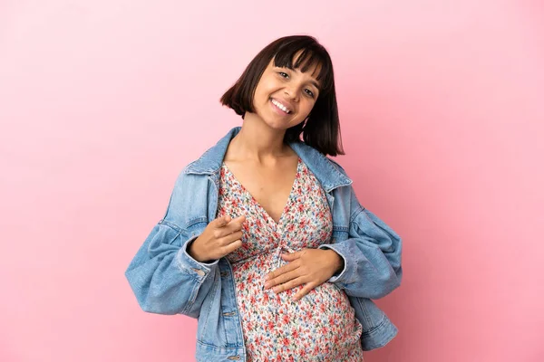 若いです妊娠中の女性上の隔離されたピンクの背景ポインティングフロントで幸せな式 — ストック写真