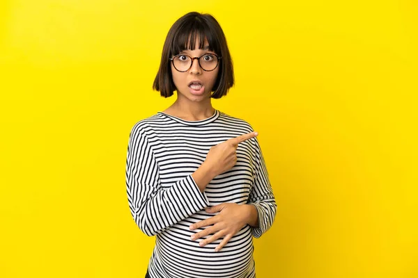 Jovem Grávida Sobre Isolado Fundo Amarelo Surpreendido Apontando Lado — Fotografia de Stock