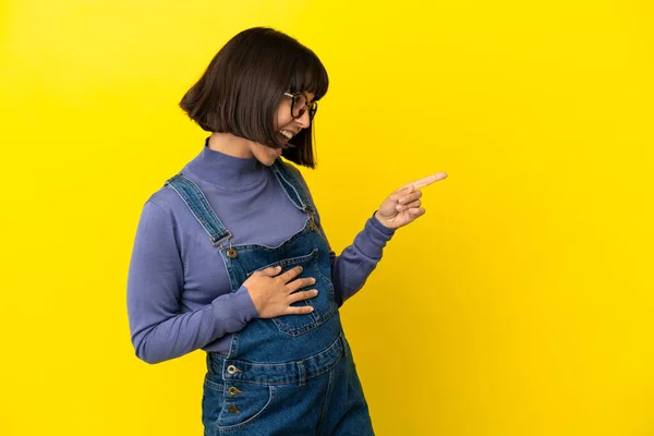 Jovem Grávida Sobre Fundo Amarelo Isolado Apontando Dedo Para Lado — Fotografia de Stock