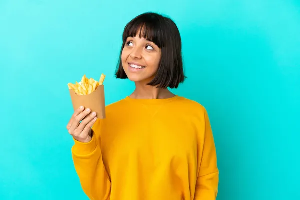 Joven Morena Sosteniendo Chips Fritos Sobre Fondo Azul Aislado Pensando —  Fotos de Stock