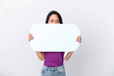 Beyaz arka planda izole edilmiş genç Vietnamlı kadın arkasında saklanan boş bir konuşma baloncuğu tutuyor.