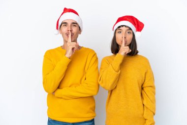 Genç melez çift, beyaz arka planda izole edilmiş bir şekilde Noel 'i kutluyor. Ağız kapama ve sessizlik işareti gösteriyor.