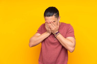 Asyalı yakışıklı adam sarı arka planda izole edilmiş ciddi bir ifadeye sahip birini sayıyor.