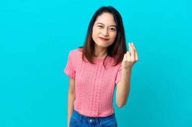 Mavi arka planda izole edilmiş genç Vietnamlı kadın İtalyan jestleri yapıyor.