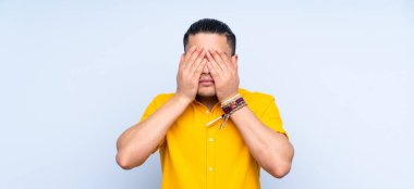 Asyalı yakışıklı adam soyutlanmış arka planda gözlerini elleriyle kapatıyor.