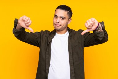 Asyalı yakışıklı adam sarı arka planda izole edilmiş. Şüpheleri var.