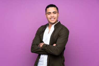 Asyalı yakışıklı adam mavi arka planda soyutlanmış, kolları bağlı ve ileriye bakıyor.