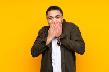 Asyalı yakışıklı adam sarı arka planda izole edilmiş. Parmaklarıyla işaret veriyor.