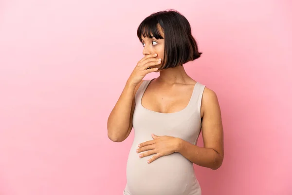 若いです妊娠女性上の隔離されたピンクの背景あります驚くべきジェスチャーをしながら見ますザサイド — ストック写真