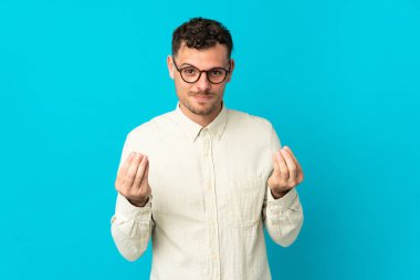 Beyaz tenli yakışıklı adam mavi arka planda izole edilmiş para hareketi yapıyor ama mahvolmuş.
