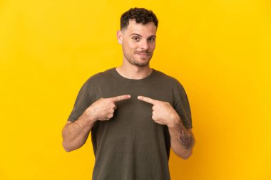 Sarı arka planda izole edilmiş beyaz, yakışıklı genç bir adam kendini işaret ediyor.