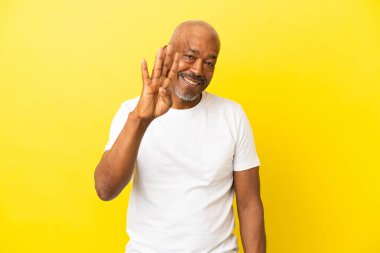 Küba Senior sarı arka planda izole edilmiş mutlu ve parmakları olan dört kişi sayıyor.