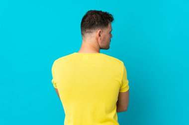 Beyaz tenli yakışıklı adam mavi arka planda izole edilmiş.