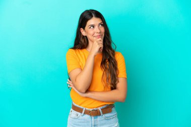 Genç beyaz kadın mavi arka planda izole edilmiş ve yukarı bakıyor.