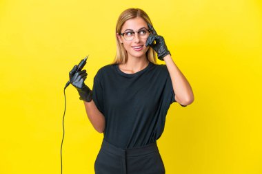 Dövme sanatçısı Uruguaylı kadın sarı arka planda izole edilmiş. Şüpheleri ve düşünceleri var.