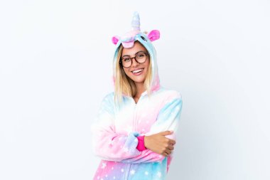 Sarışın Uruguaylı kız tek boynuzlu at pijaması giyiyor beyaz arka planda gözlüklü ve gülümseyen.