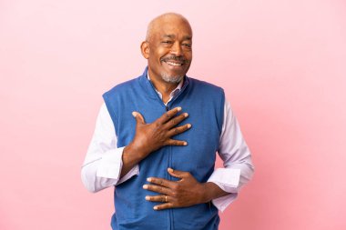 Kübalı son sınıf öğrencisi pembe arka planda çok gülümsüyor.