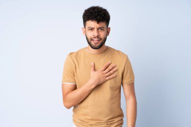 Mavi arka planda izole edilmiş genç Faslı adam kendini işaret ediyor.