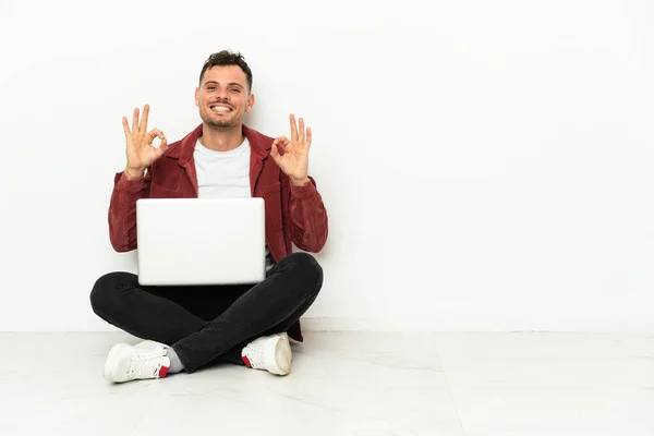 Jovem Bonito Caucasiano Sentar Chão Com Laptop Mostrando Sinal Com — Fotografia de Stock