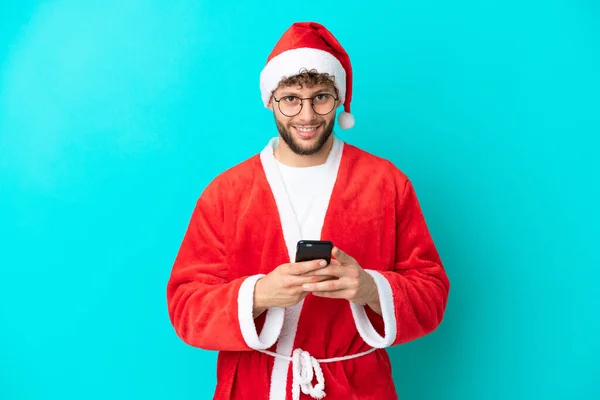 Молодой Человек Замаскированный Санта Клауса Изолированный Синем Фоне Отправляет Сообщение — стоковое фото