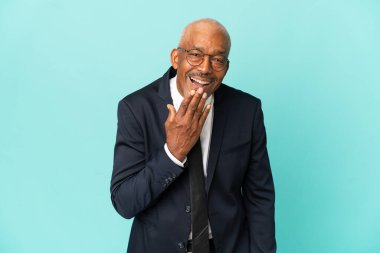 İşletme son sınıf öğrencisi mavi arka planda izole edilmiş mutlu ve güler yüzlü, ağzı kapalı biri.