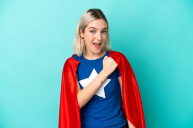 Süper kahraman beyaz kadın mavi arka planda izole bir şekilde zaferi kutluyor.