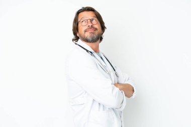 Beyaz arka planda izole edilmiş yaşlı bir Hollandalı doktor önlüğü giymiş ve kollarını kavuşturmuş.