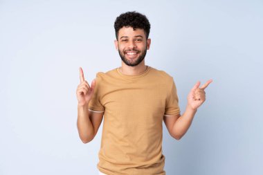 Faslı genç bir adam mavi arka planda izole edilmiş. Harika bir fikre işaret ediyor.